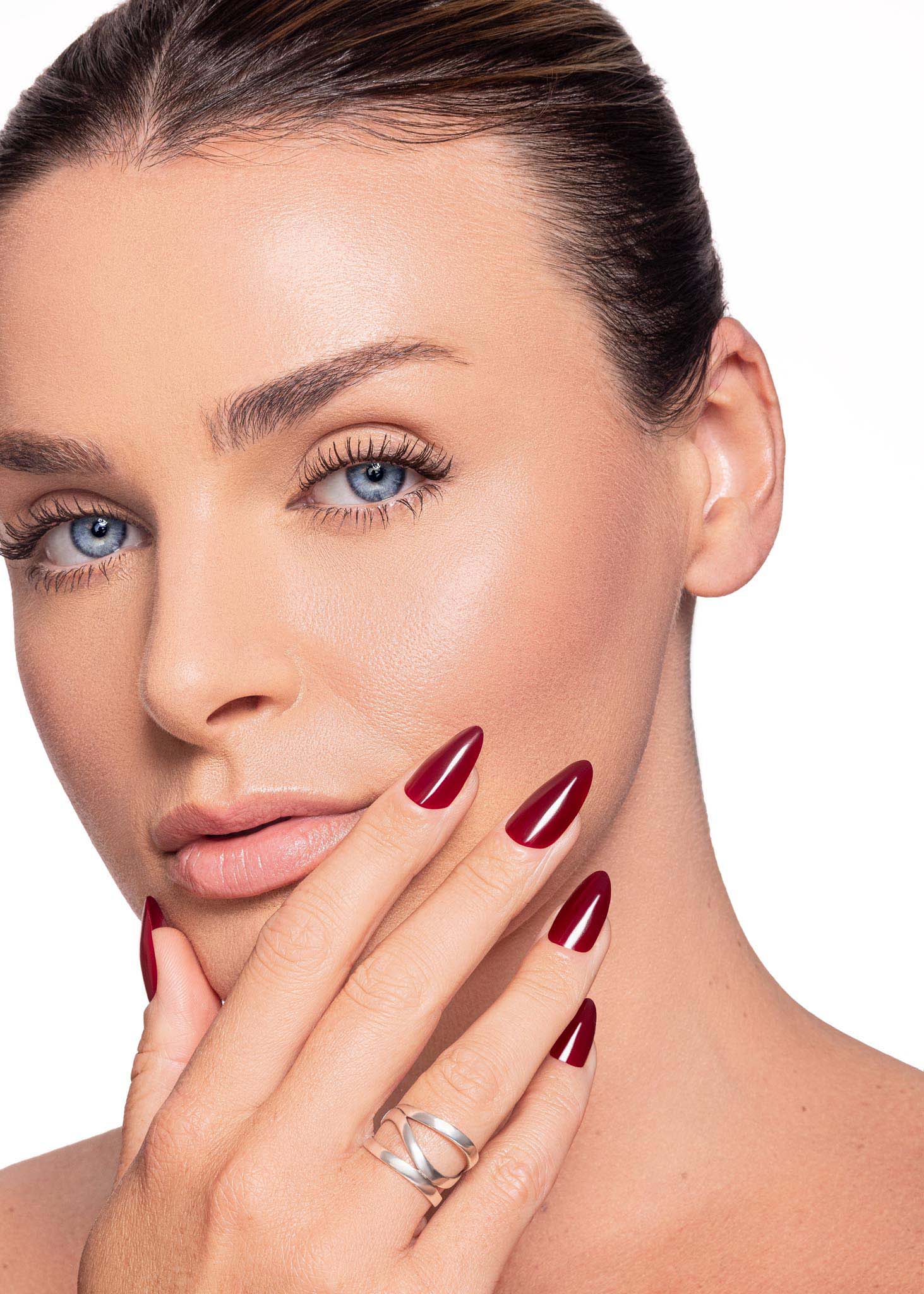female model showing hand and nails. nail color maroon red. nail shape medium almond
