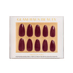 Glam Haus Beauty press-on nails packaging with gold accents on a white background, Burgandy red nails color, medium almond shaped nails 
